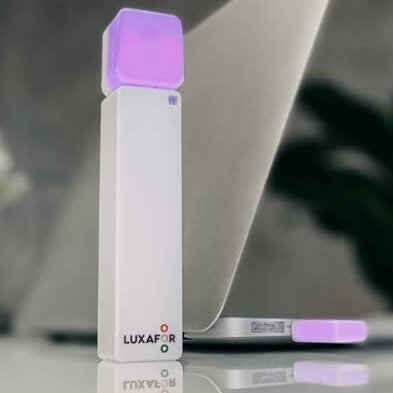 Luxafor Bluetooth Busylight, weiss auf Tisch von Computer leuchtet lila