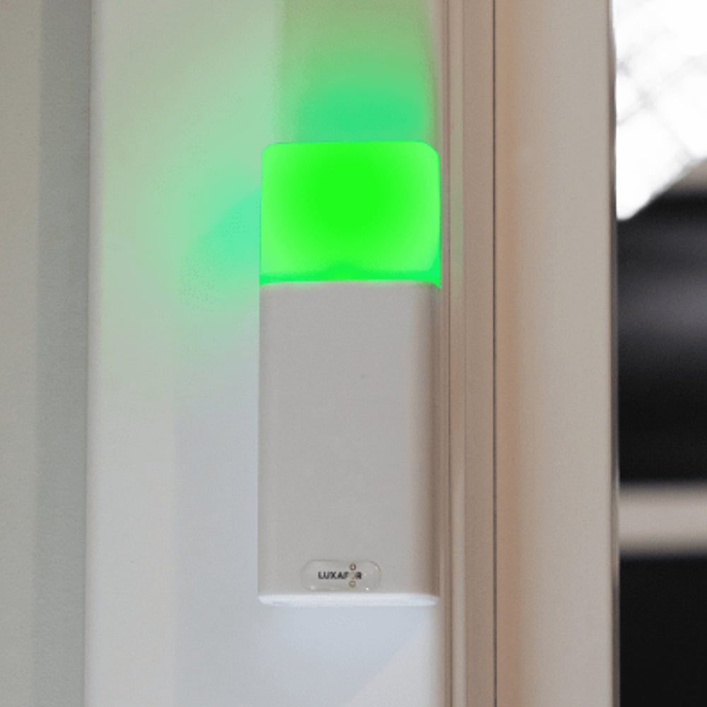 Luxafor Bluetooth Pro Busylight weiss leuchtet grün an der Wand des Besprechungsraums